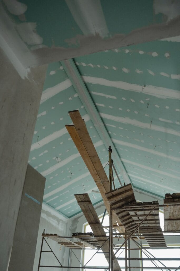 Illustrative library photograph, not an Elbaz project: a ceiling under construction, with services and scaffolding above the grid