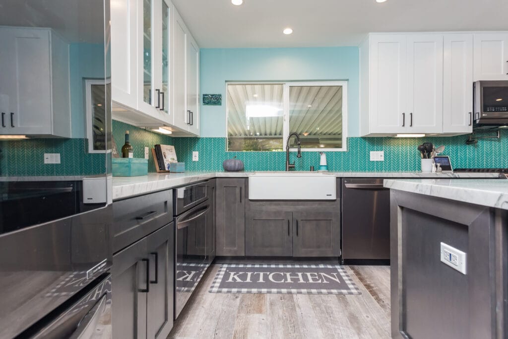 Two-tone kitchen with teal herringbone backsplash and marble waterfall island — view 8