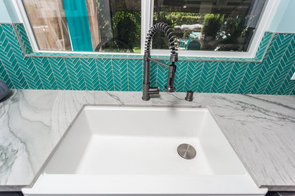 Two-tone kitchen with teal herringbone backsplash and marble waterfall island — view 12