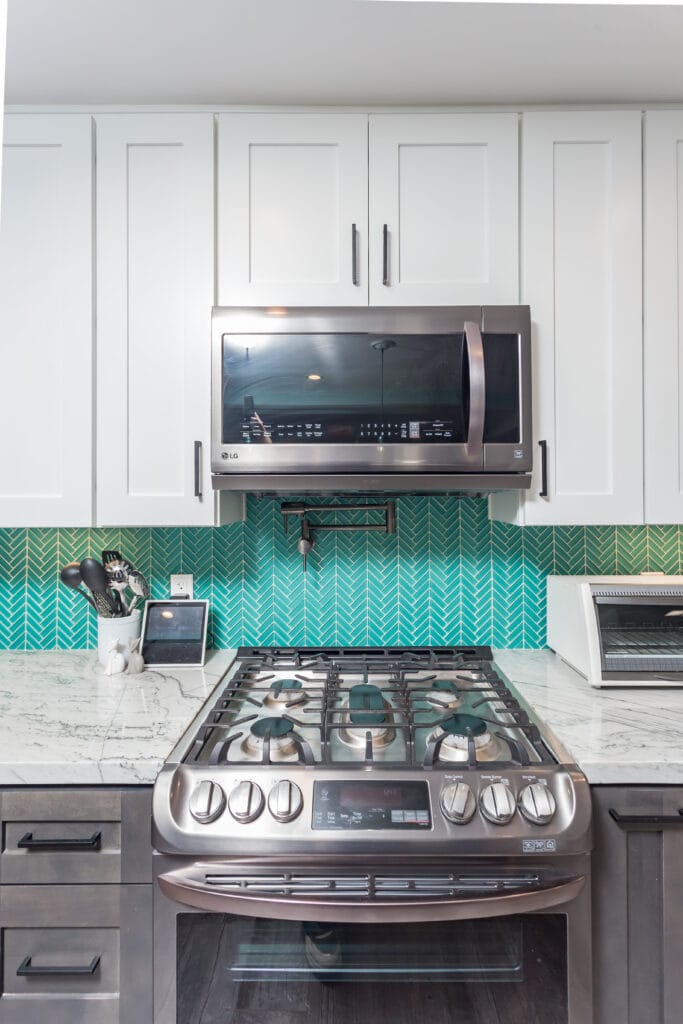 Two-tone kitchen with teal herringbone backsplash and marble waterfall island — view 15