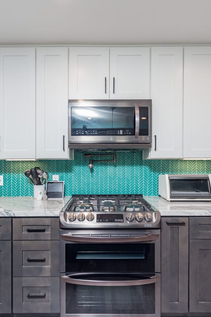 Two-tone kitchen with teal herringbone backsplash and marble waterfall island — view 16