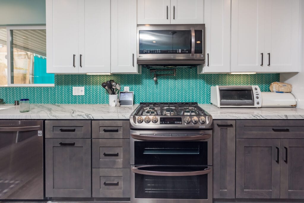 Two-tone kitchen with teal herringbone backsplash and marble waterfall island — view 17