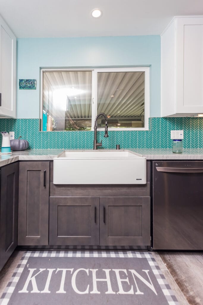 Two-tone kitchen with teal herringbone backsplash and marble waterfall island — view 18