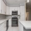 White shaker kitchen with quartz waterfall island and brushed-nickel hardware — view 1