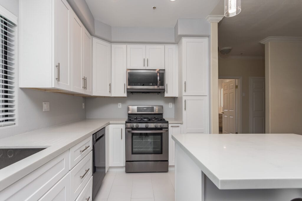 White shaker kitchen with quartz waterfall island and brushed-nickel hardware — view 1