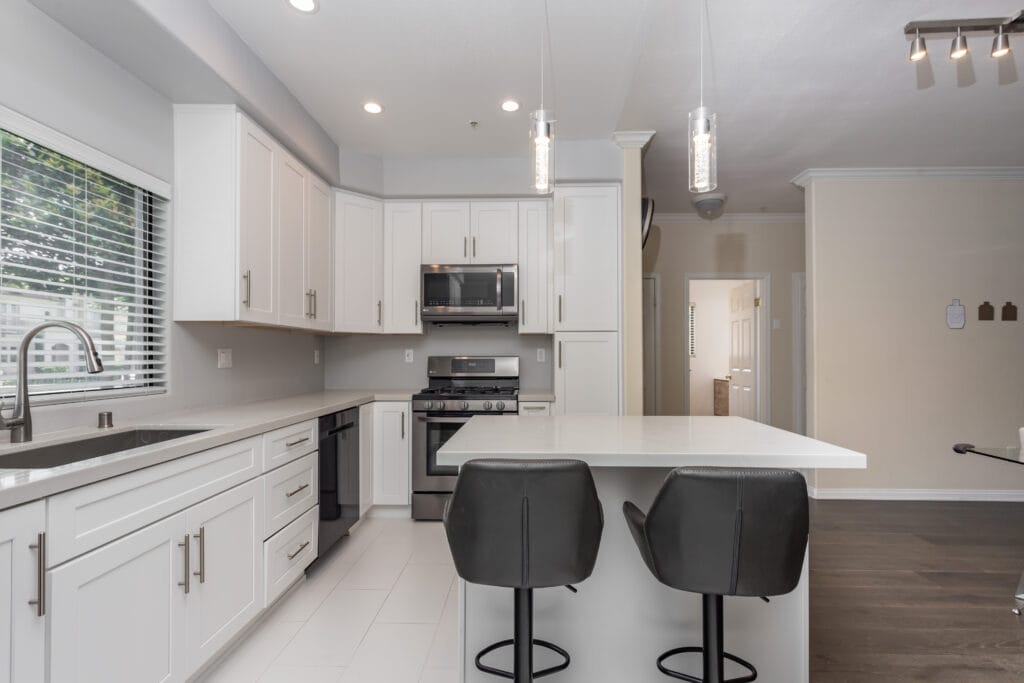 White shaker kitchen with quartz waterfall island and brushed-nickel hardware — view 2