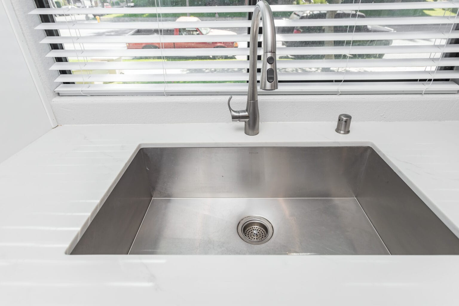 Close detail of the undermount sink and pull-down mixer set into the quartz worktop at the window