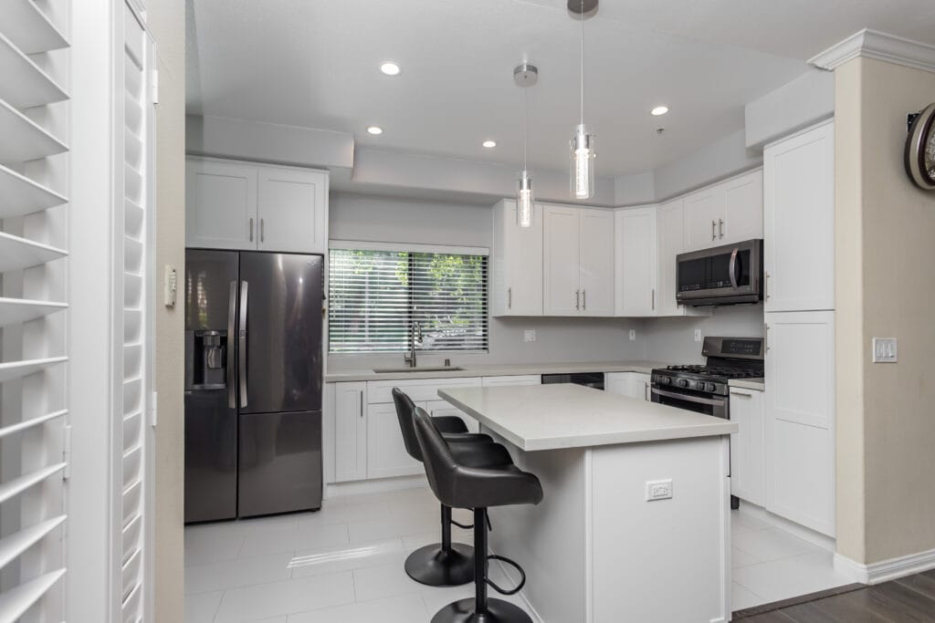 White shaker kitchen with quartz waterfall island and brushed-nickel hardware — view 7