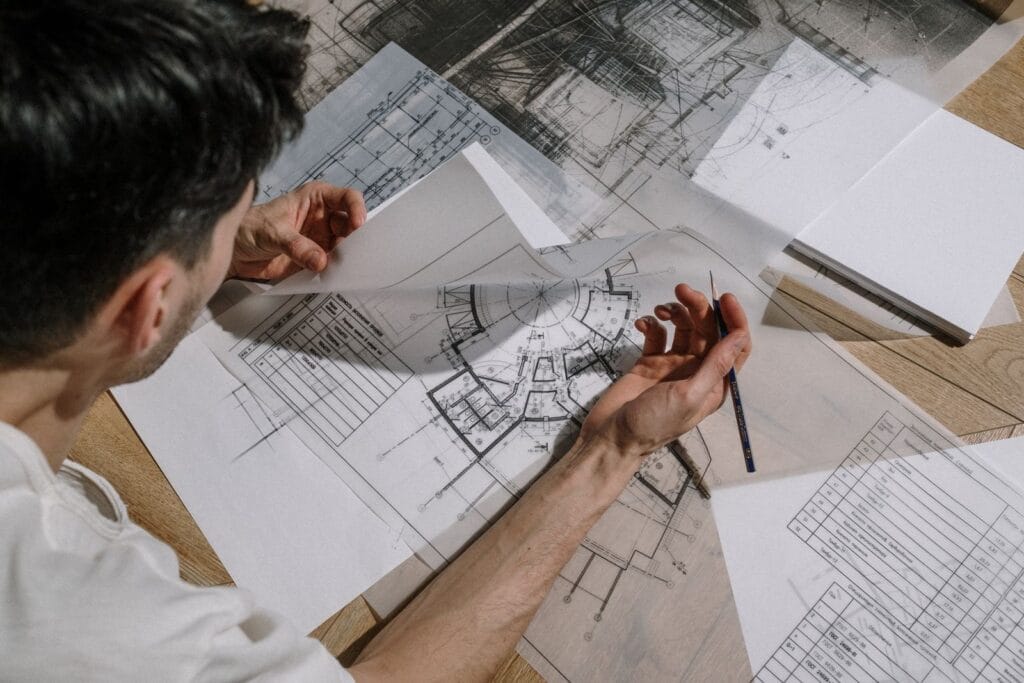 Illustrative library photograph, not an Elbaz project: an architect reviewing a detailed building floor plan