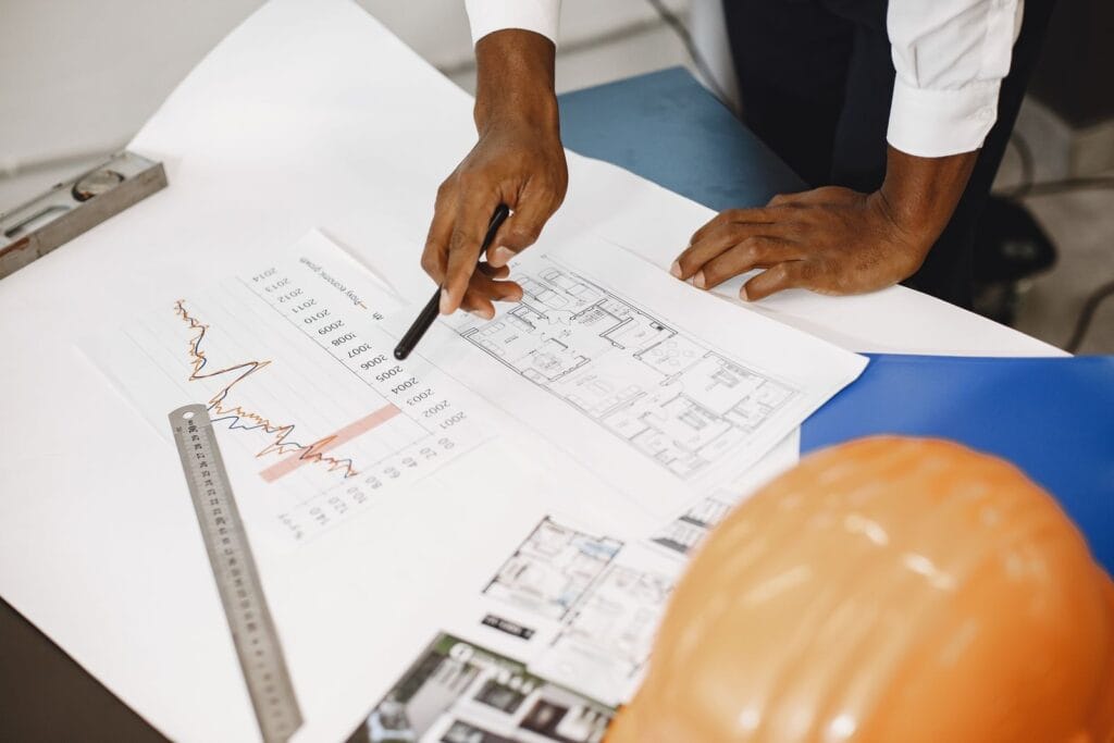 Illustrative library photograph, not an Elbaz project: a hand pointing at a floor plan alongside a finishes schedule