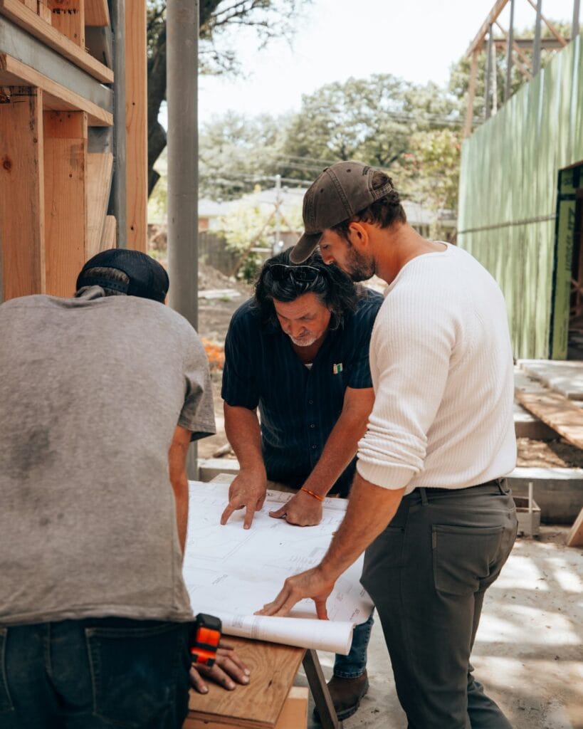 Illustrative library photograph, not an Elbaz project: drawings being reviewed on site by a group in work clothes