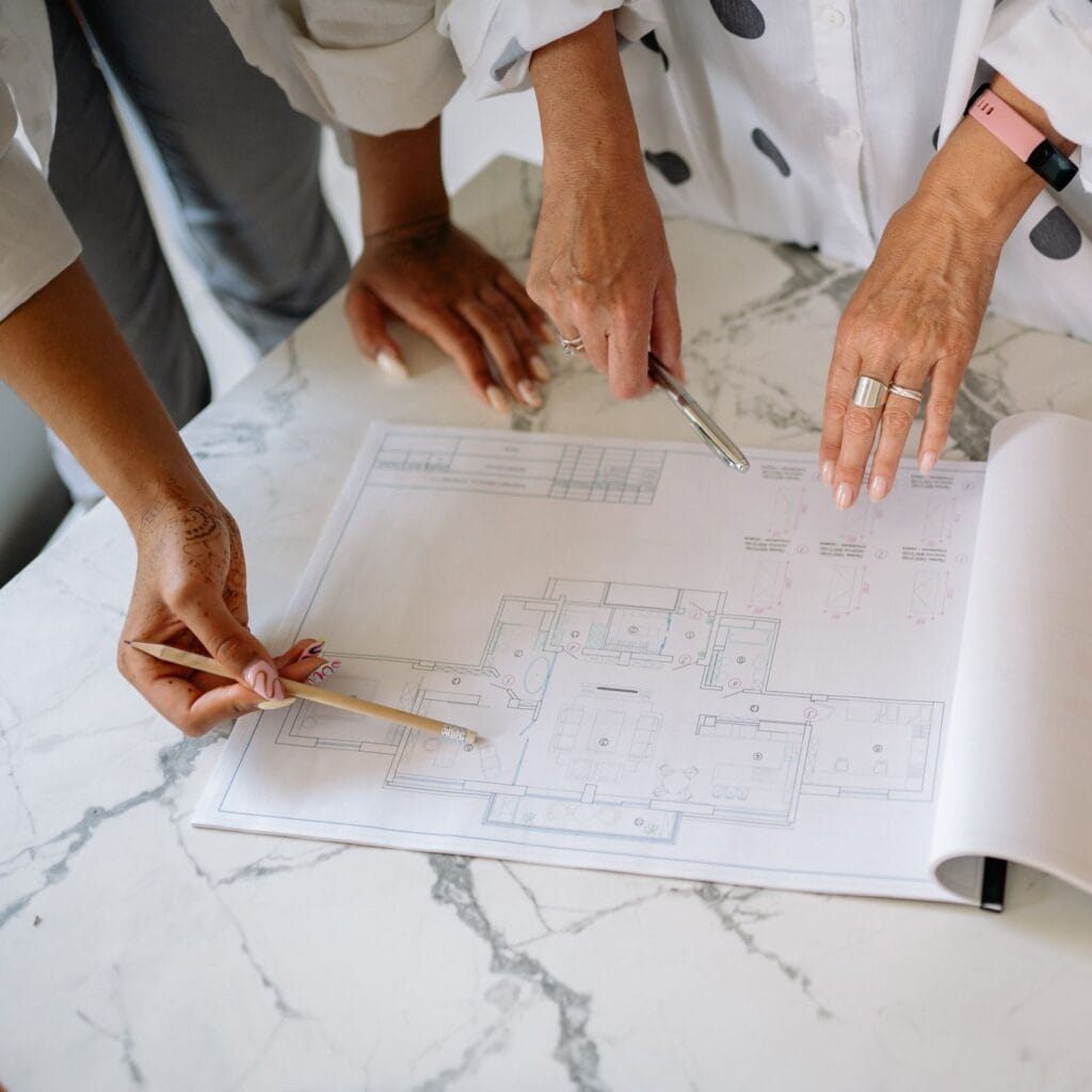 Illustrative library photograph, not an Elbaz project: three people reviewing a coloured floor plan together