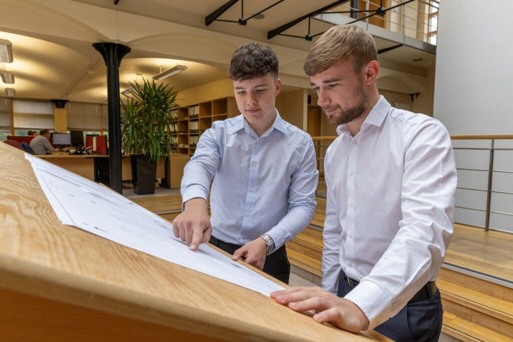 Illustrative library photograph, not an Elbaz project: two professionals reviewing blueprints across a table