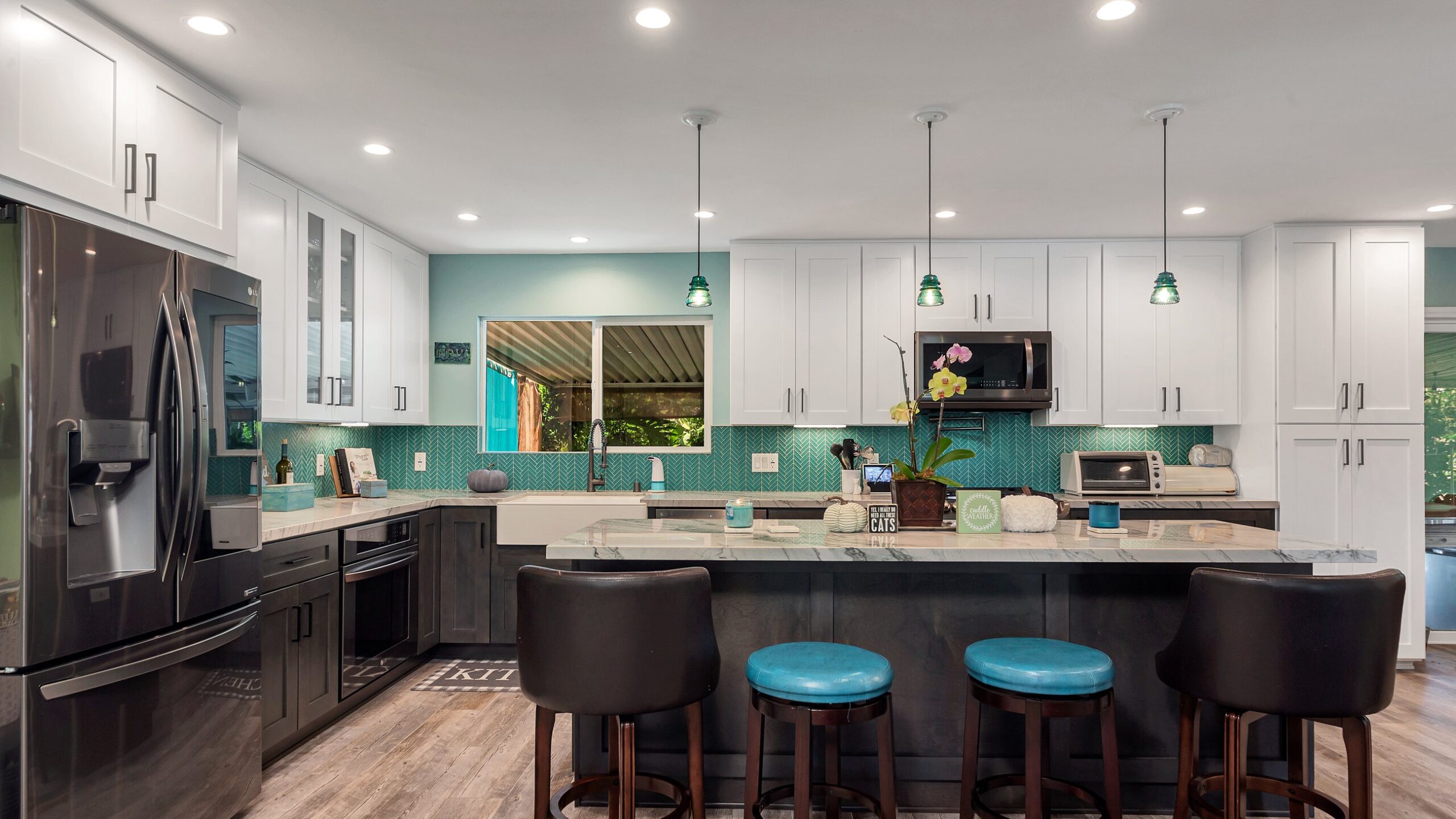 Completed kitchen with a dark stained shaker island, painted perimeter cabinetry, quartz worktops and a teal herringbone backsplash