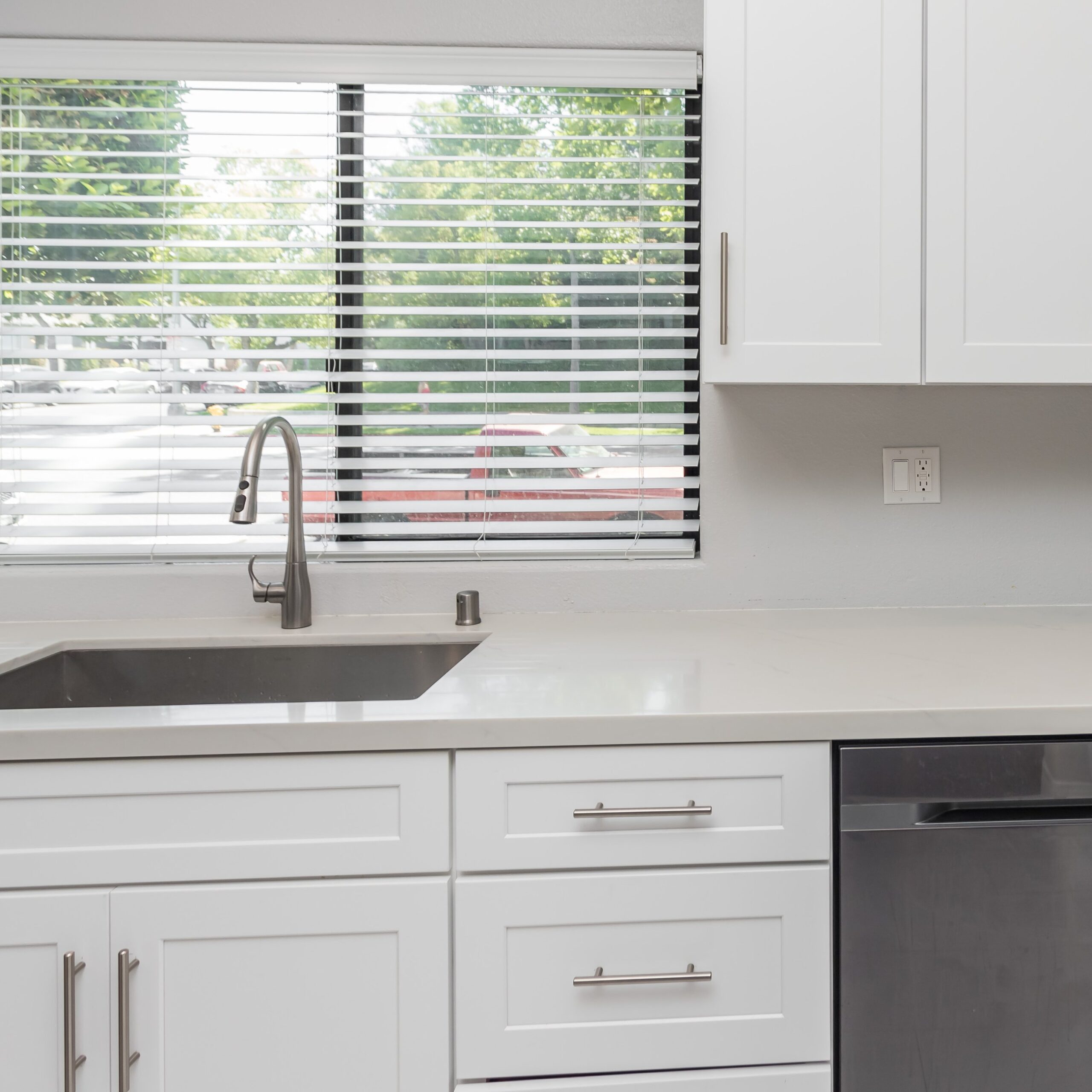 White shaker base cabinets and drawer fronts with bar pulls beside a dishwasher