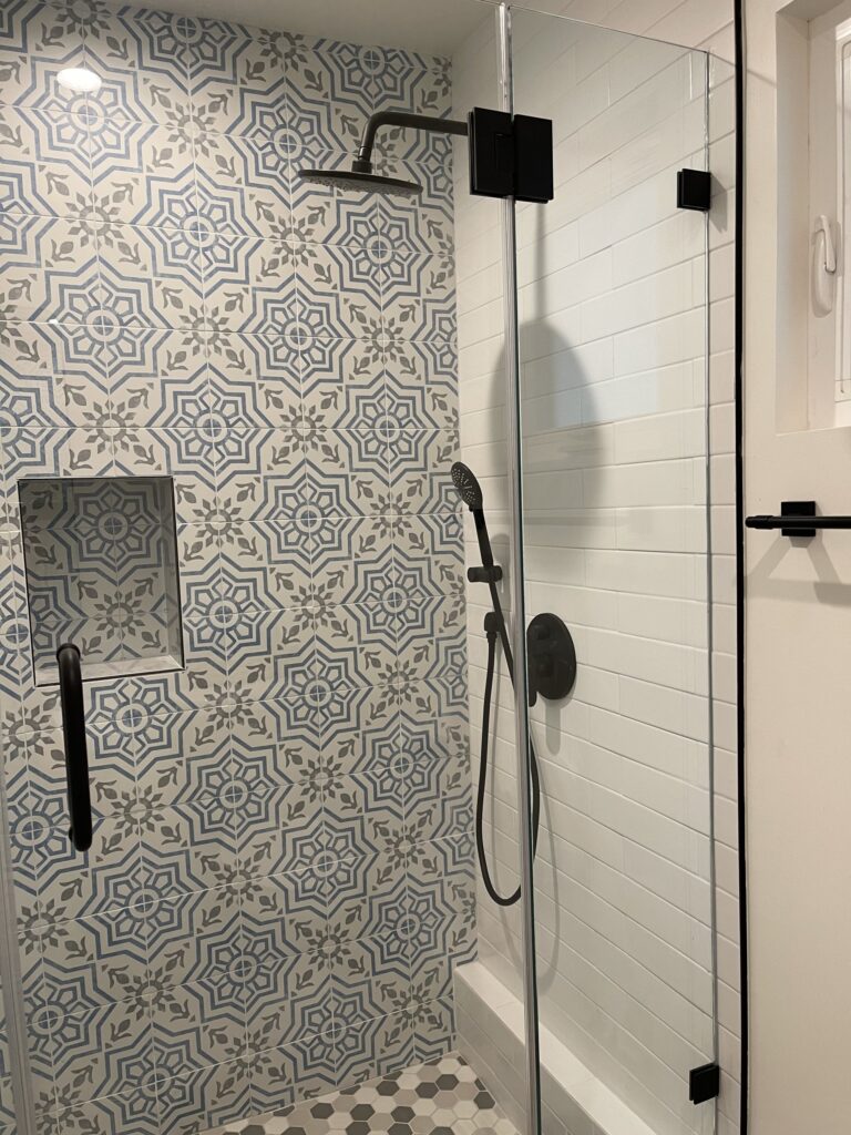 ADU shower with a patterned feature wall, white subway tile, a recessed niche and matte black fittings
