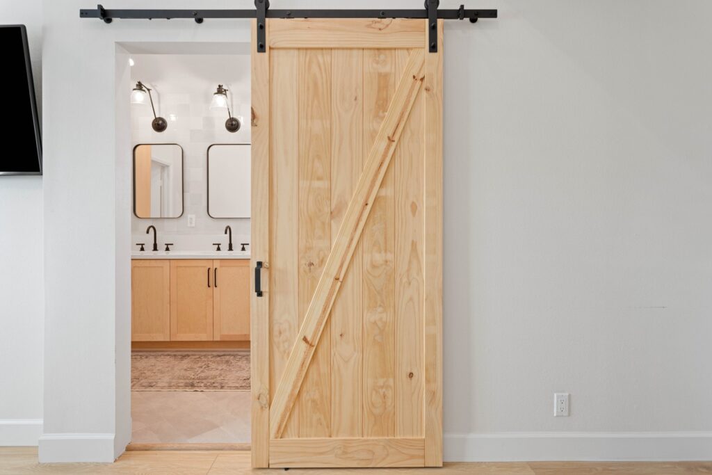 Primary bath suite seen through its sliding barn door, with the double vanity beyond