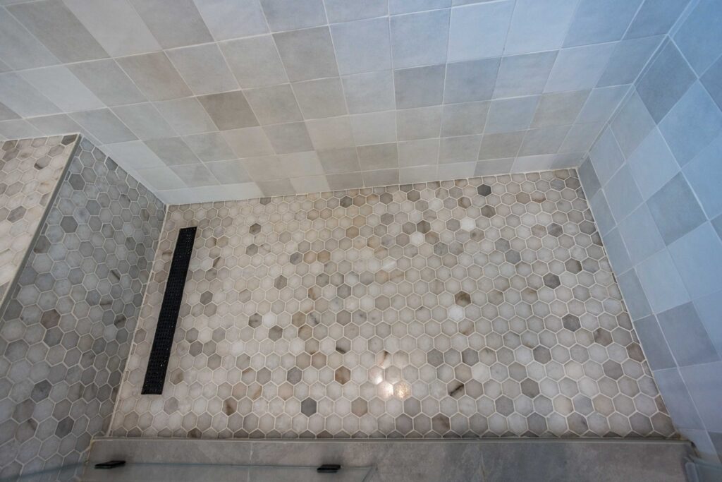 Shower floor in hexagonal mosaic with a linear drain at the threshold