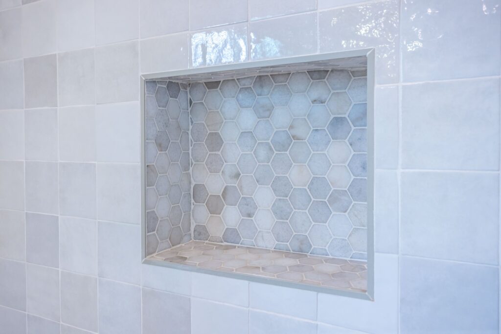 Recessed shower niche lined in hexagonal mosaic