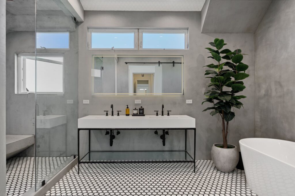 Floating console vanity on a black steel frame over penny-round mosaic