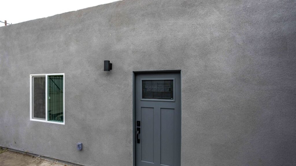 Completed small stucco cottage with a grey entry door, built by Elbaz Construction in South Florida