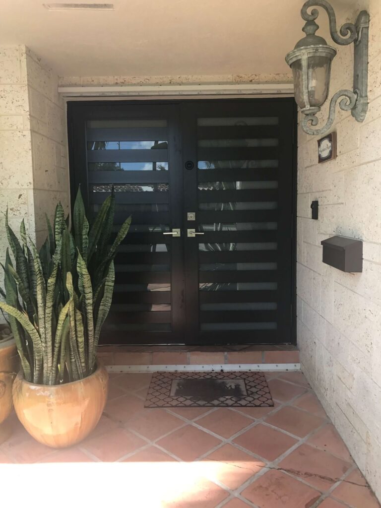 Elbaz installation: impact entry door with horizontal glazed bars, set in a stucco surround
