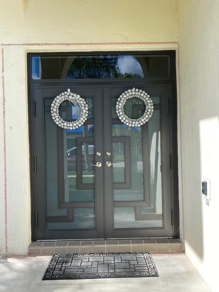 Elbaz installation: double impact entry doors with a geometric glazing pattern and arched transom