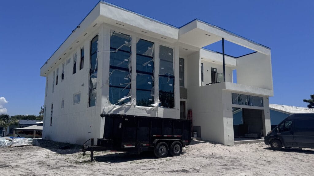 Two-storey canal-front home by Elbaz Construction with the structure complete and impact glazing installed