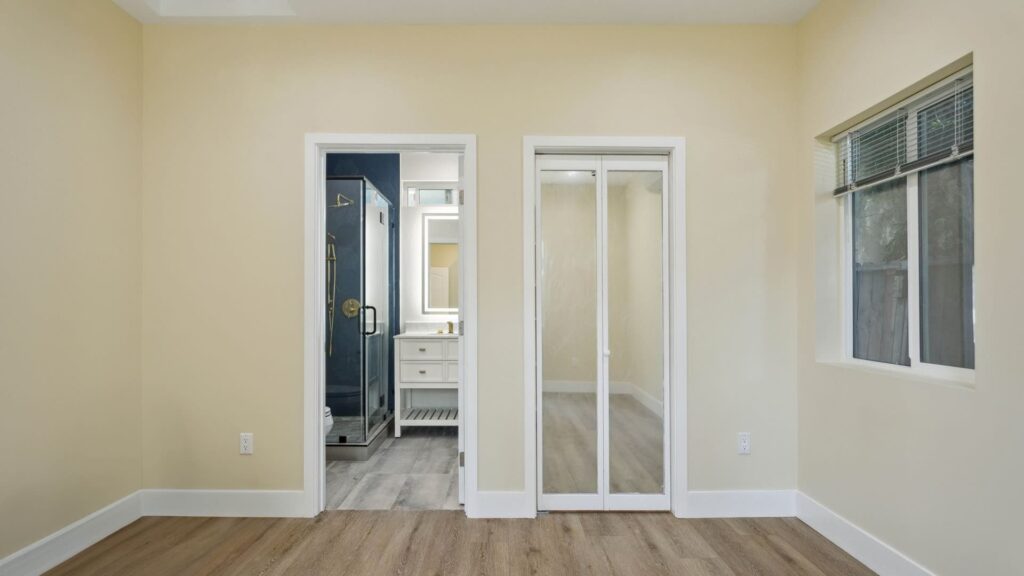 Completed bedroom with mirrored closet doors in a guest-house conversion by Elbaz Construction in South Florida
