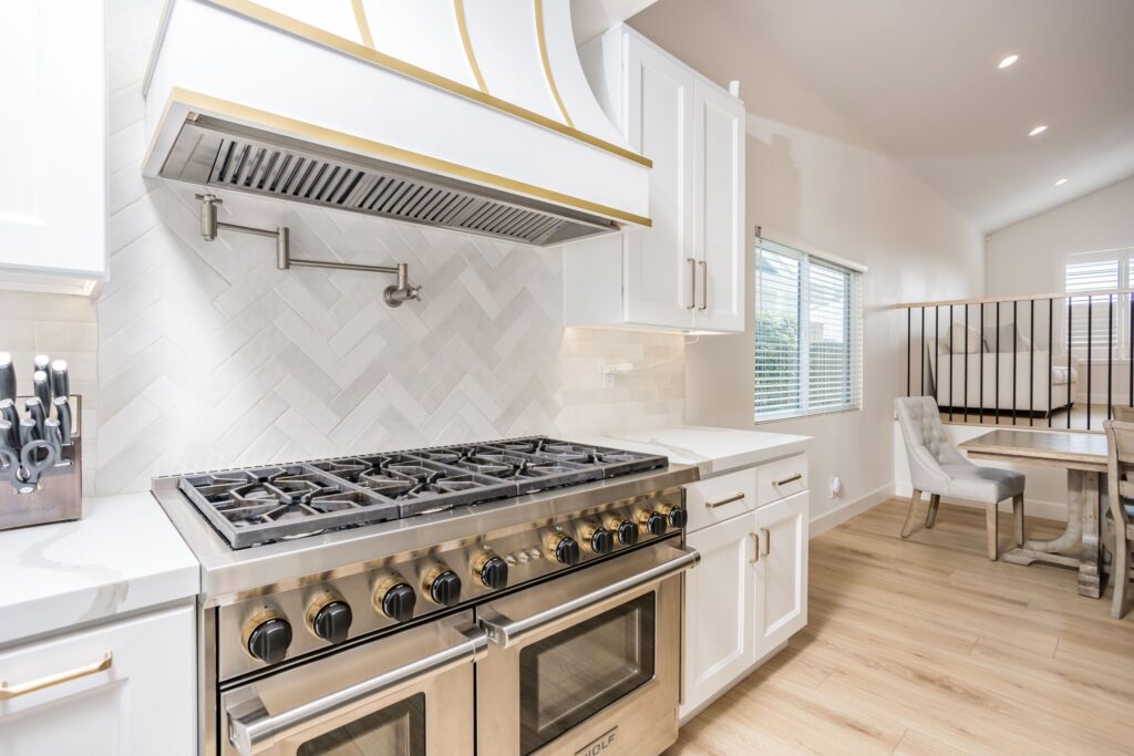 Range wall with a herringbone splashback and a brass pot filler