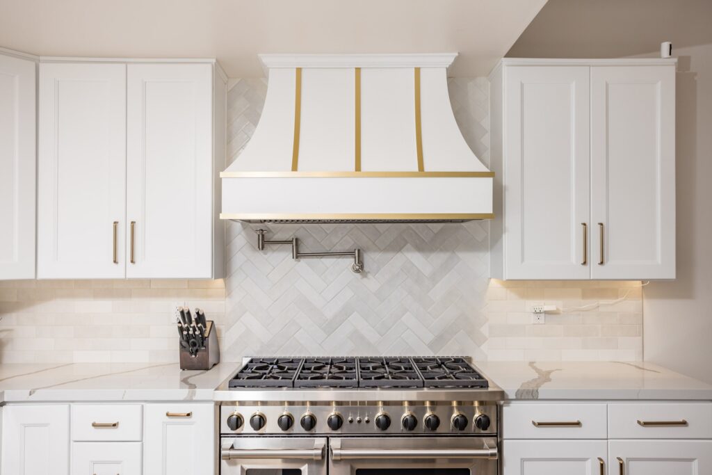 Custom hood with brass strapping between full-height cabinet banks