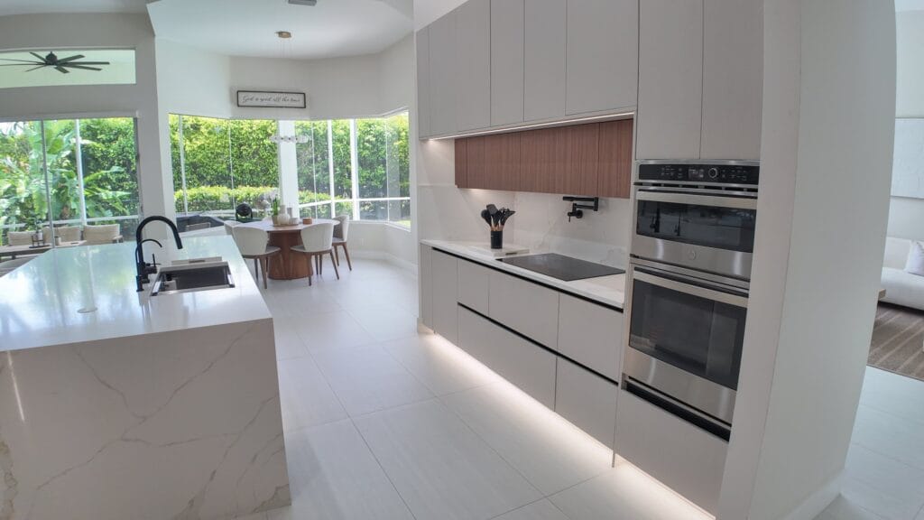 Kitchen island and run seen towards the glazing, with a wall oven stack and induction hob set into the worktop