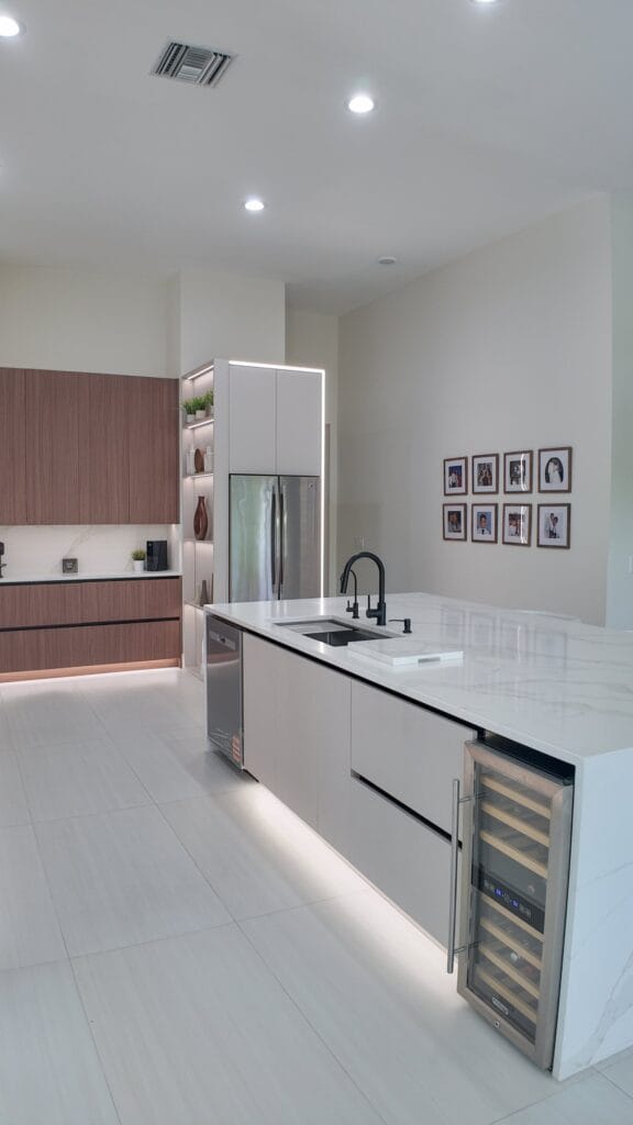 Tall storage bank and integrated refrigeration at the end of the kitchen run, with an undercounter wine cabinet in the island