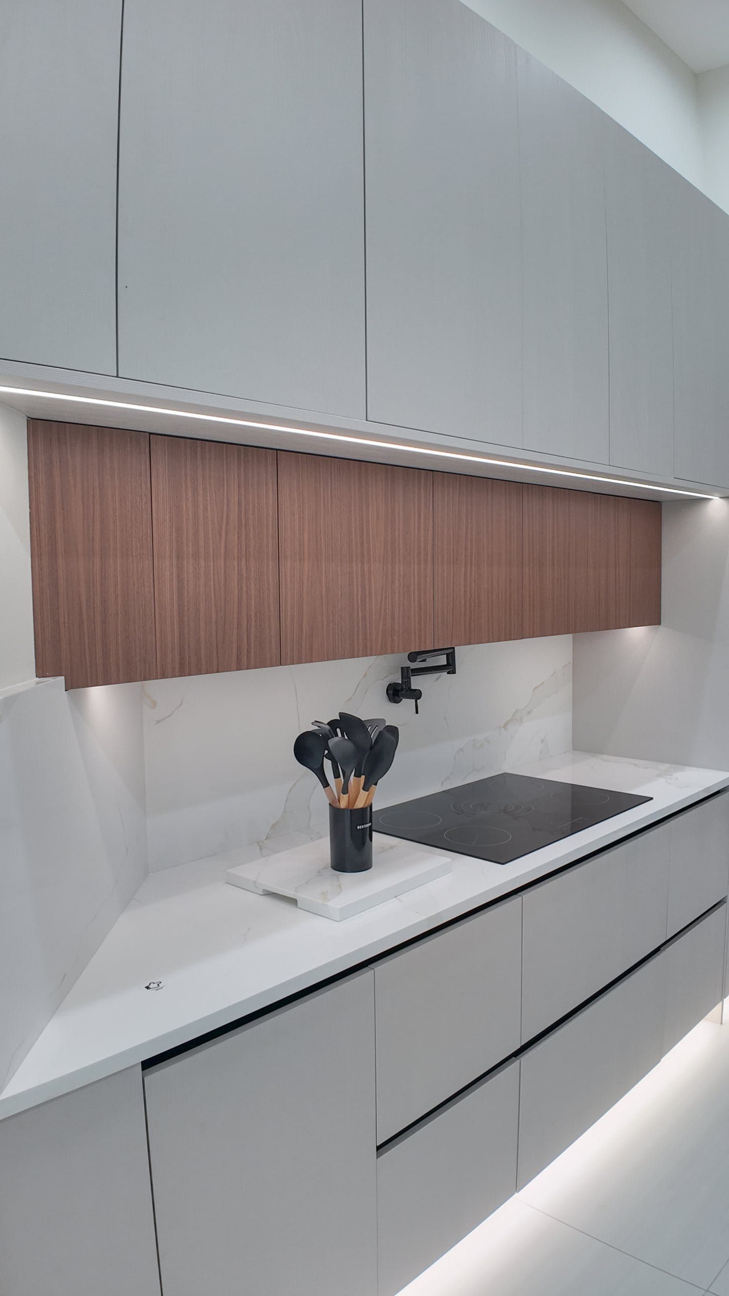 Handleless upper cabinetry with continuous LED cove lighting above the worktop