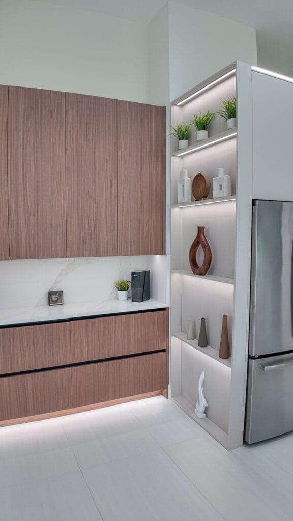 Open shelving niche lit from within, between the walnut tall run and the integrated refrigeration