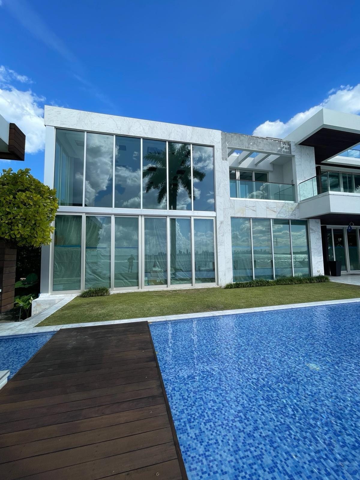 Floor-to-ceiling impact glazing across the rear elevation of a South Florida house, seen across the pool deck