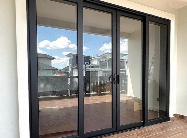 Elbaz installation: dark-framed multi-slide impact door opening onto a tiled terrace