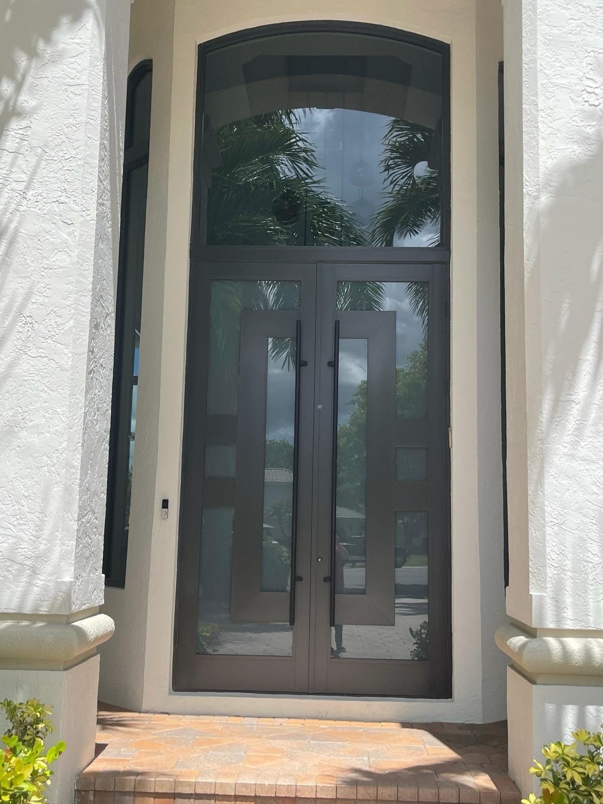 Impact entry door with an arched transom set into a rendered surround