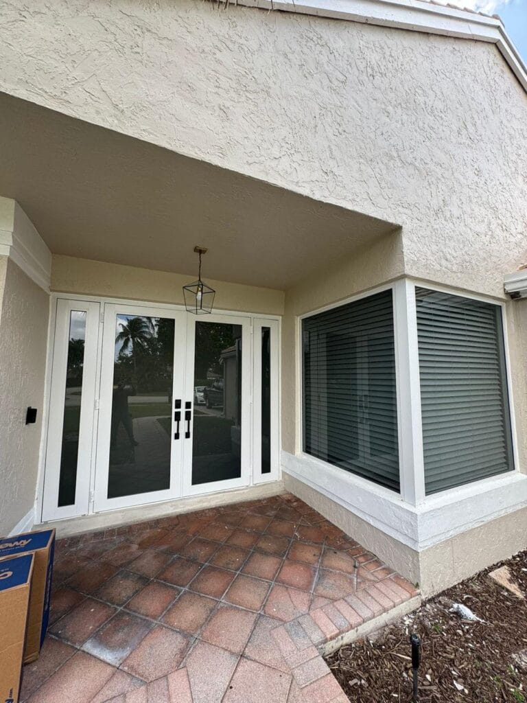 Impact window run and glazed french doors under a covered entry, with the packaging still on site