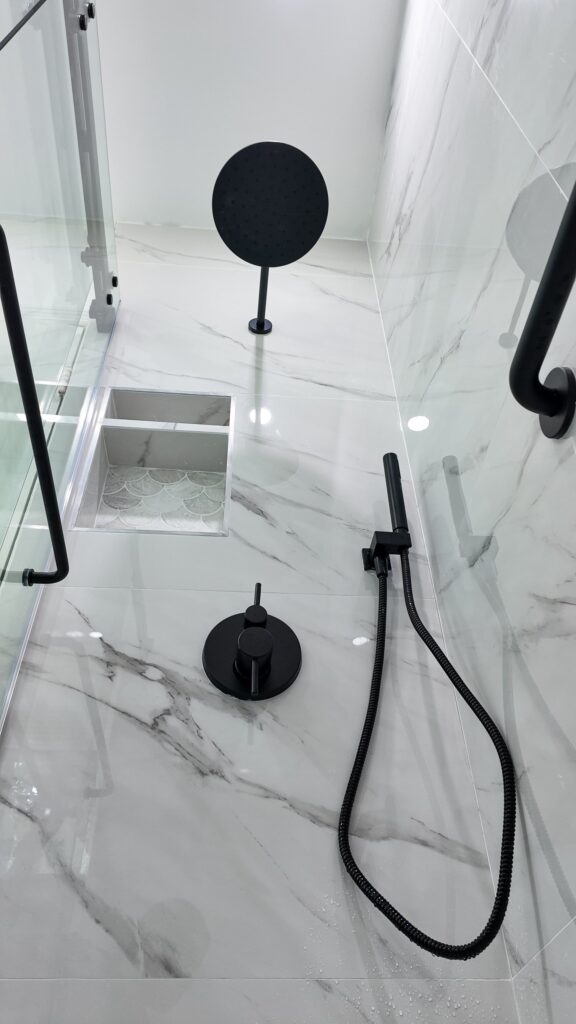 Walk-in shower with a wall-mounted grab bar and a hand shower on a slide rail