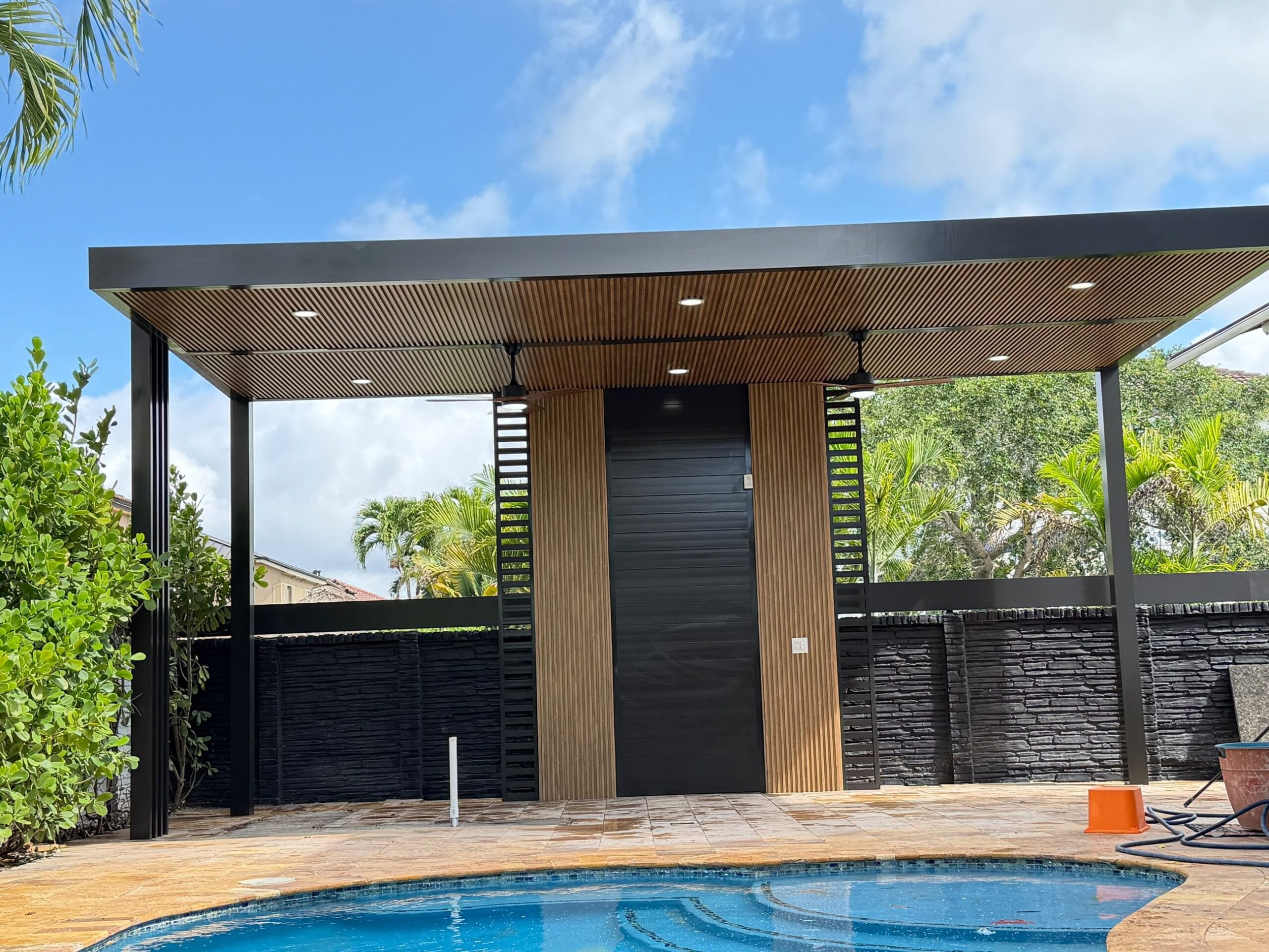 Poolside pavilion with timber-slat soffit and dark split-face stone wall behind