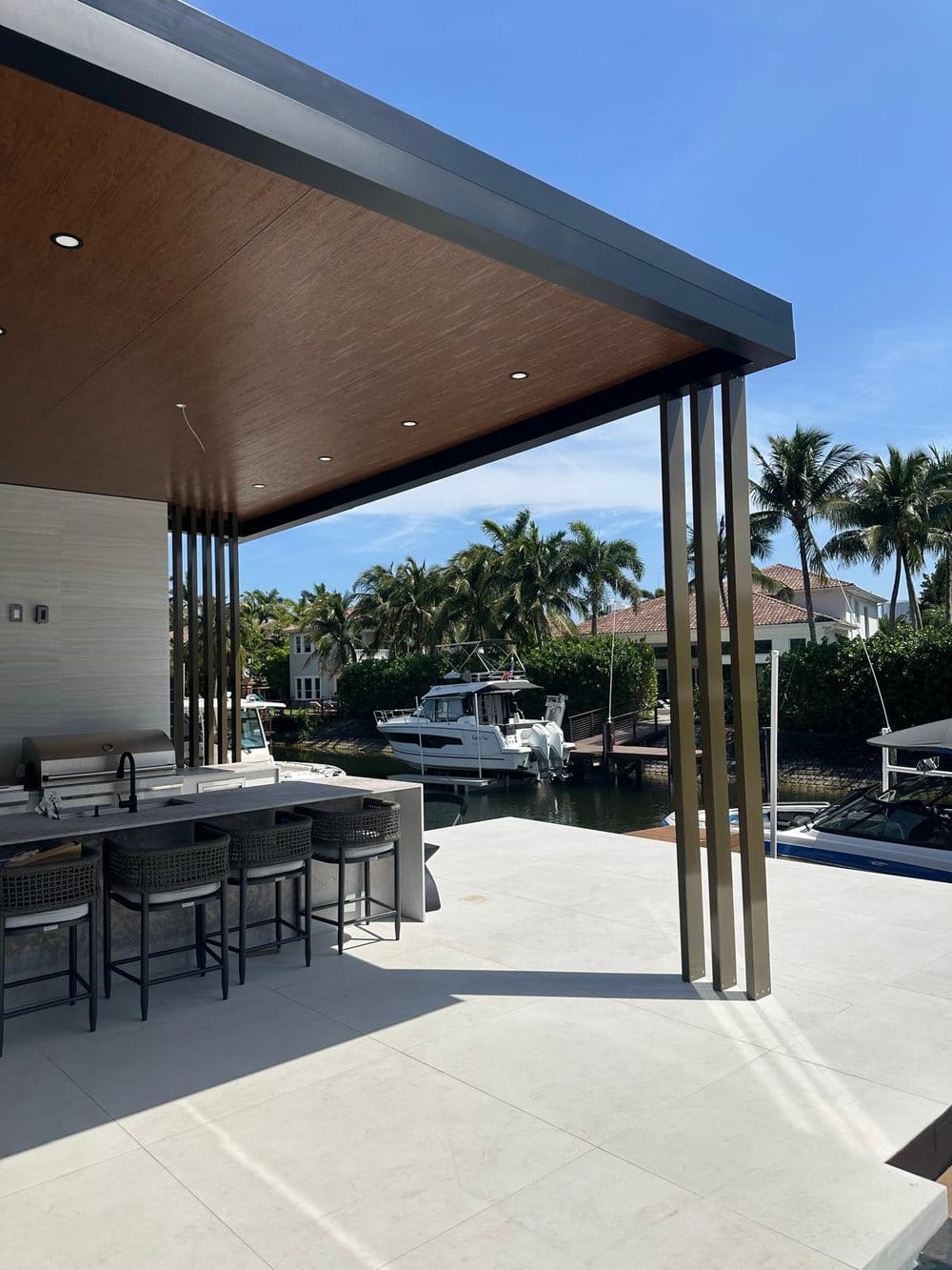 Covered outdoor kitchen framed on the canal rather than the garden, on an Elbaz Construction project in South Florida