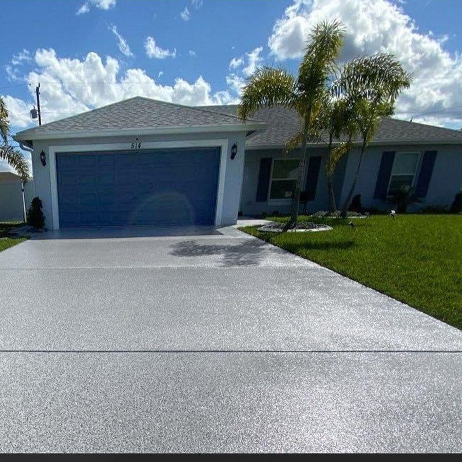 Textured concrete driveway finished across the full width of a single-storey home, running up to a closed garage door