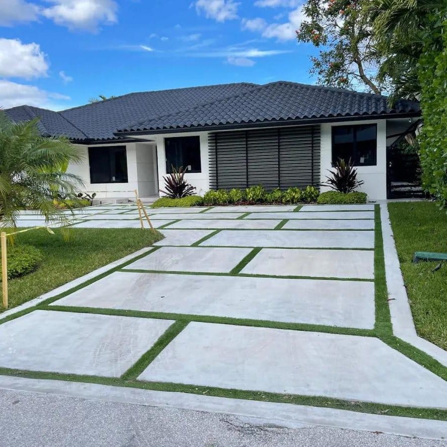 Concrete ribbon driveway with planted grass joints leading to a modern home