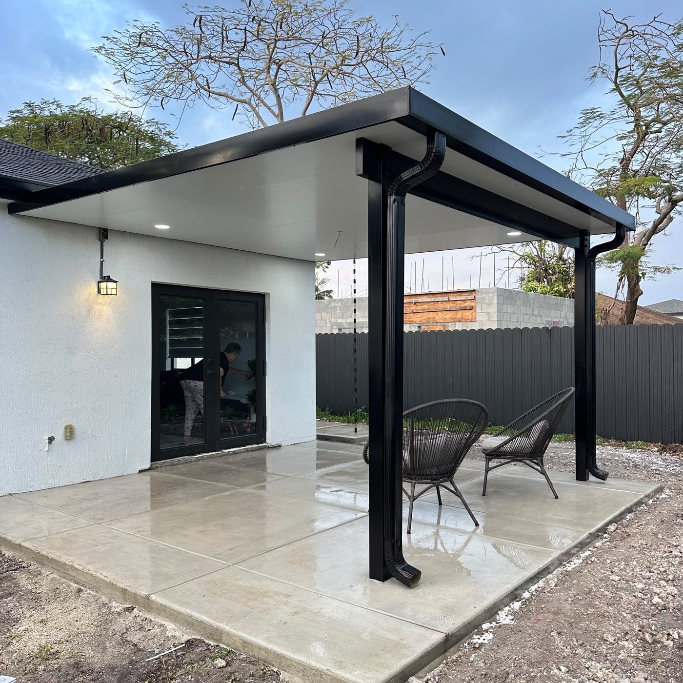 Attached cover with a dark frame and white soffit over a concrete deck