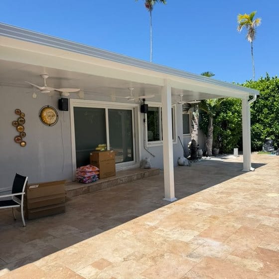 A covered walkway along the rear of a house, finished in travertine and running the length of the elevation