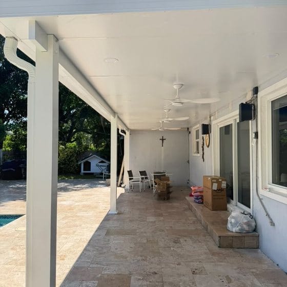 Long covered terrace with a white soffit running over travertine paving