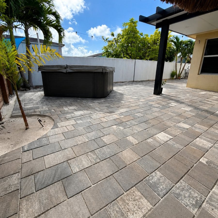 Travertine patio with a hot tub beneath a tiki structure and palms