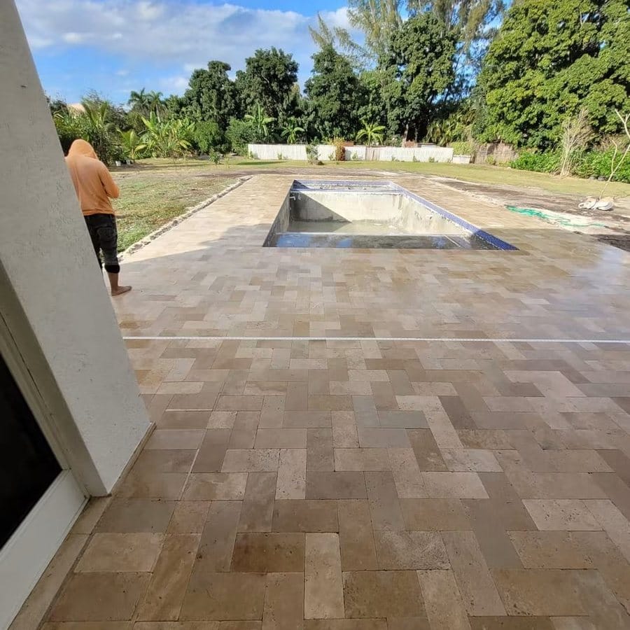 Travertine pool deck under construction around a rectangular pool and spa