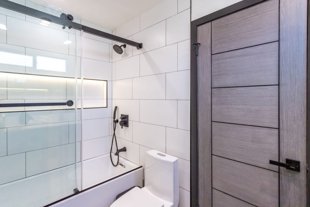 The same bath from the doorway, timber door edge in the foreground